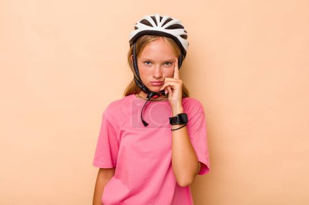 Téléchargez les photos : Petite fille caucasienne portant un casque de vélo isolé sur fond beige pointant temple avec le doigt, pensant, concentré sur une tâche. - en image libre de droit