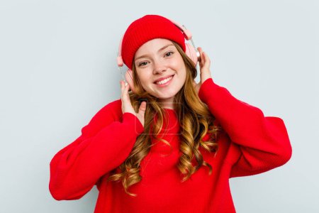Téléchargez les photos : Jeune femme caucasienne portant des écouteurs isolés sur fond bleu - en image libre de droit