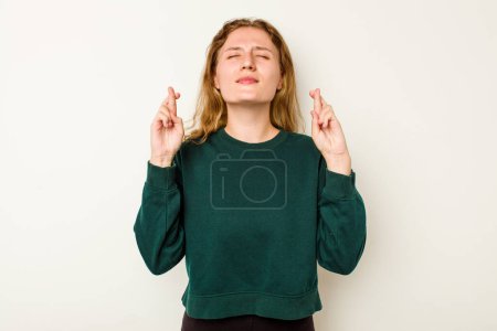 Téléchargez les photos : Jeune femme caucasienne isolée sur fond blanc croisant les doigts pour avoir de la chance - en image libre de droit