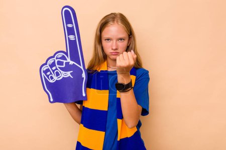 Photo for Little caucasian sports fan girl isolated on beige background showing fist to camera, aggressive facial expression. - Royalty Free Image