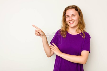 Foto de Joven mujer caucásica aislada sobre fondo blanco sonriendo alegremente señalando con el dedo índice de distancia. - Imagen libre de derechos