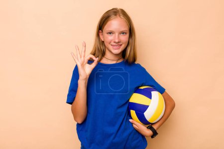 Téléchargez les photos : Petite fille caucasienne jouant au volley isolé sur fond beige joyeux et confiant montrant ok geste. - en image libre de droit