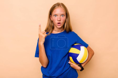 Téléchargez les photos : Petite fille caucasienne jouant au volley isolé sur fond beige ayant une bonne idée, concept de créativité. - en image libre de droit