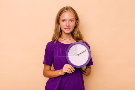 Photo for Little caucasian girl holding a clock isolated on beige background happy, smiling and cheerful. - Royalty Free Image