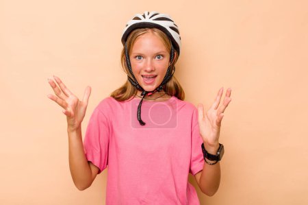 Photo for Little caucasian girl wearing a bike helmet isolated on beige background receiving a pleasant surprise, excited and raising hands. - Royalty Free Image