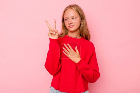 Téléchargez les photos : Caucasien adolescent fille isolé sur fond rose prendre un serment, mettre la main sur la poitrine. - en image libre de droit
