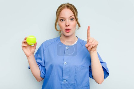 Téléchargez les photos : Jeune kinésithérapeute caucasien tenant une balle de tennis isolée sur fond bleu ayant une bonne idée, concept de créativité. - en image libre de droit