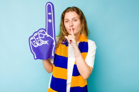 Téléchargez les photos : Jeune femme fan de sport caucasienne isolée sur fond bleu gardant un secret ou demandant le silence. - en image libre de droit