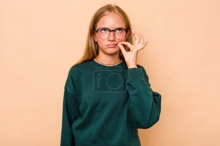 Téléchargez les photos : Caucasien adolescent fille isolé sur fond beige avec les doigts sur les lèvres garder un secret. - en image libre de droit