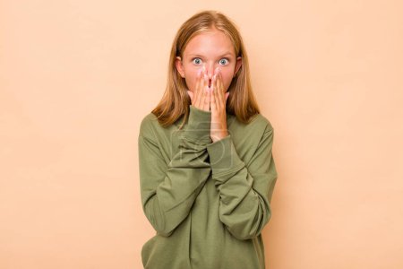 Photo for Caucasian teen girl isolated on beige background shocked, covering mouth with hands, anxious to discover something new. - Royalty Free Image