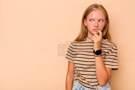 Téléchargez les photos : Caucasien adolescent fille isolé sur fond beige détendu penser à quelque chose en regardant un espace de copie. - en image libre de droit
