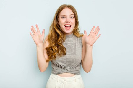 Photo for Young caucasian woman isolated on blue background receiving a pleasant surprise, excited and raising hands. - Royalty Free Image