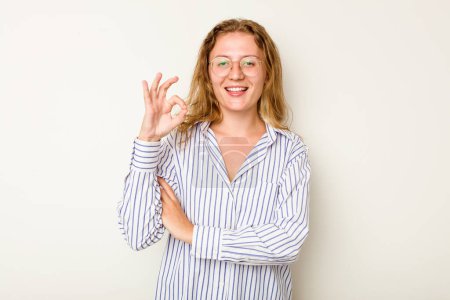 Foto de Joven mujer caucásica aislada sobre fondo blanco guiña un ojo y sostiene un gesto bien con la mano. - Imagen libre de derechos