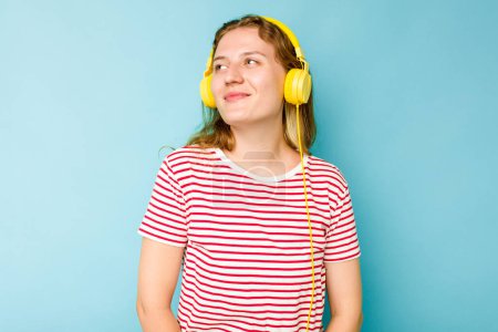 Photo for Young caucasian woman wearing headphones isolated on blue background dreaming of achieving goals and purposes - Royalty Free Image
