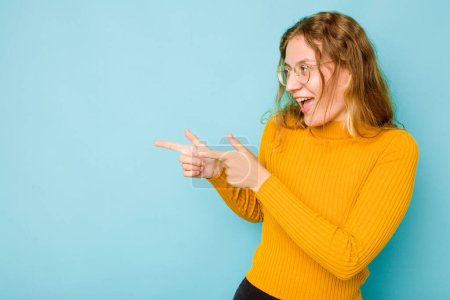 Photo for Young caucasian woman isolated on blue background points with thumb finger away, laughing and carefree. - Royalty Free Image