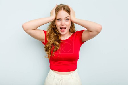 Photo for Young caucasian woman isolated on blue background screaming, very excited, passionate, satisfied with something. - Royalty Free Image