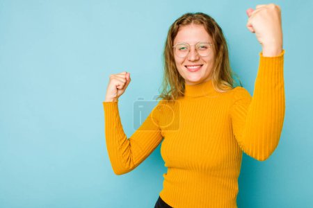 Photo for Young caucasian woman isolated on blue background raising fist after a victory, winner concept. - Royalty Free Image