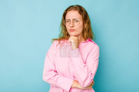 Photo for Young caucasian woman isolated on blue background suspicious, uncertain, examining you. - Royalty Free Image