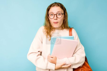 Photo for Young student caucasian woman isolated on blue background shrugs shoulders and open eyes confused. - Royalty Free Image
