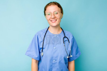 Téléchargez les photos : Jeune infirmière caucasienne isolée sur fond bleu heureux, souriant et joyeux. - en image libre de droit