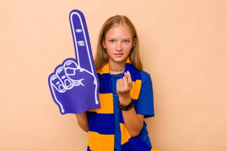 Photo for Little caucasian sports fan girl isolated on beige background pointing with finger at you as if inviting come closer. - Royalty Free Image