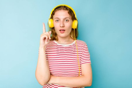 Téléchargez les photos : Jeune femme caucasienne portant des écouteurs isolés sur fond bleu ayant une bonne idée, concept de créativité. - en image libre de droit