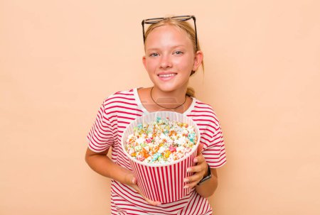 Photo for Little caucasian girl eating popcorn isolated on beige background - Royalty Free Image