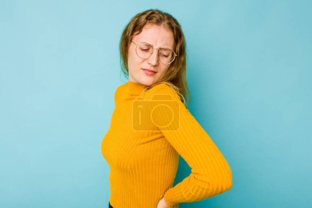 Téléchargez les photos : Jeune femme caucasienne isolée sur fond bleu souffrant d'un mal de dos. - en image libre de droit