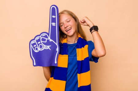 Photo for Little caucasian sports fan girl isolated on beige background raising fist after a victory, winner concept. - Royalty Free Image