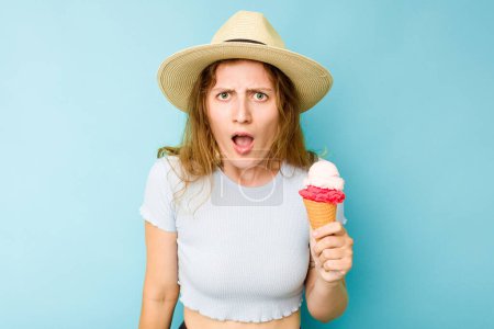 Téléchargez les photos : Jeune femme caucasienne tenant une crème glacée isolé un fond bleu criant très en colère et agressif. - en image libre de droit