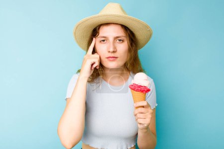 Téléchargez les photos : Jeune femme caucasienne tenant une crème glacée isolé un fond bleu pointant temple avec le doigt, penser, concentré sur une tâche. - en image libre de droit