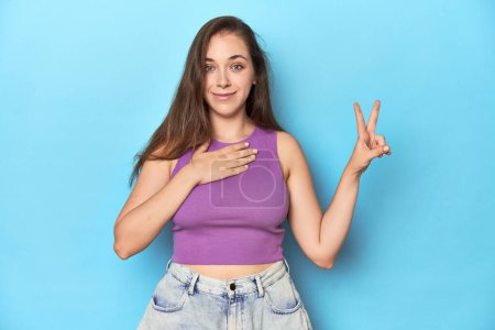 Photo for Fashionable young woman in a purple top on blue background taking an oath, putting hand on chest. - Royalty Free Image
