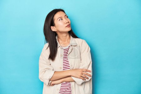 Photo for Asian woman in layered shirt and striped t-shirt, dreaming of achieving goals and purposes - Royalty Free Image
