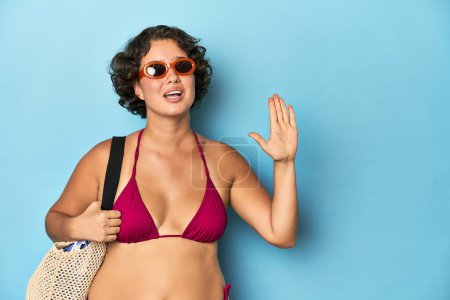 Foto de Mujer joven en bikini con bolsa de playa sonriente alegre mostrando el número cinco con los dedos. - Imagen libre de derechos
