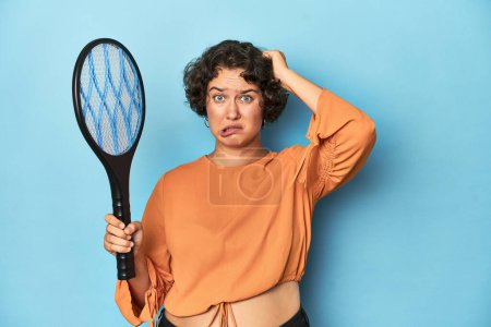 Photo for Young woman with electric mosquito racket Young woman with electric mosquito racketbeing shocked, she has remembered important meeting. - Royalty Free Image