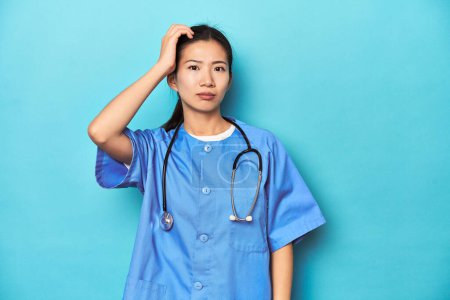 Téléchargez les photos : Infirmière asiatique avec stéthoscope, prise de vue en studio médical, choquée, elle s'est souvenue d'une réunion importante. - en image libre de droit