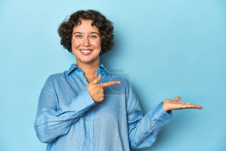 Photo for Young Caucasian woman with short hair excited holding a copy space on palm. - Royalty Free Image