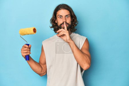 Photo for Bearded man painting with a yellow roller keeping a secret or asking for silence. - Royalty Free Image