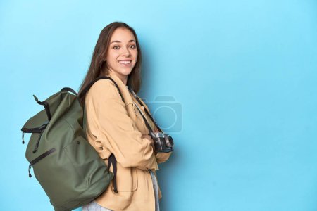 Foto de Mujer viajera con cámara vintage y mochila en azul. - Imagen libre de derechos