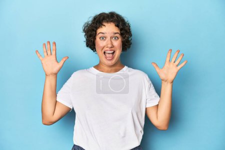 Photo for Young Caucasian woman with short hair receiving a pleasant surprise, excited and raising hands. - Royalty Free Image