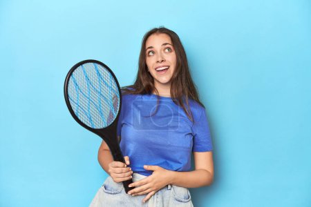Photo for Woman with an electric bug zapper on a blue background dreaming of achieving goals and purposes - Royalty Free Image