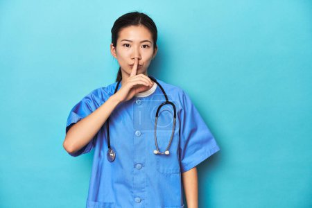 Photo for Asian nurse with stethoscope, medical studio shot, keeping a secret or asking for silence. - Royalty Free Image