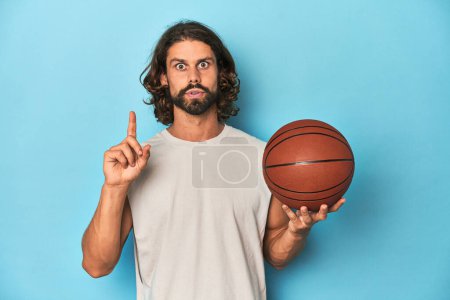 Photo for Bearded man with basketball in blue studio having some great idea, concept of creativity. - Royalty Free Image