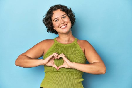 Photo for Young Caucasian woman with short hair smiling and showing a heart shape with hands. - Royalty Free Image