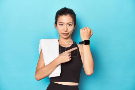 Téléchargez les photos : Sportswoman montrant fonction smartwatch, toile de fond de studio. - en image libre de droit