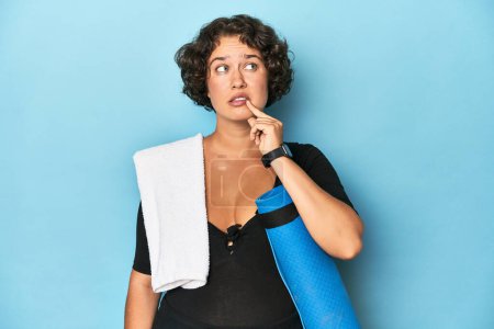 Photo for Athletic young woman with yoga mat relaxed thinking about something looking at a copy space. - Royalty Free Image