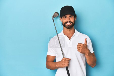 Foto de Golfista de pelo largo con club y sombrero sonriendo y levantando el pulgar hacia arriba - Imagen libre de derechos