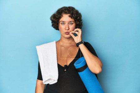 Photo for Athletic young woman with yoga mat with fingers on lips keeping a secret. - Royalty Free Image