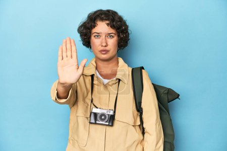 Foto de Mujer viajero joven con cámara vintage de pie con la mano extendida mostrando señal de stop, lo que le impide. - Imagen libre de derechos