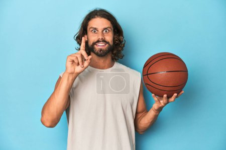Photo for Bearded man with basketball in blue studio having an idea, inspiration concept. - Royalty Free Image